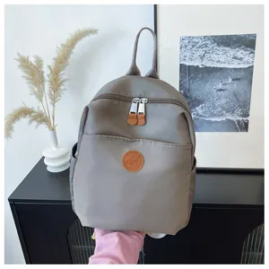 Detail view of khaki nylon backpack with durable leather zippers and round logo plaque