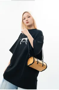 Street style view of a bright yellow cylindrical crossbody bag with black trim detail