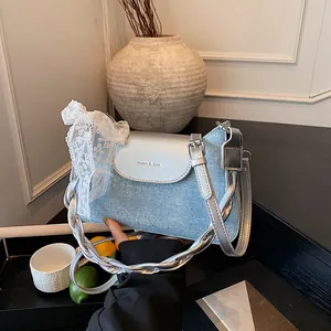 Blue denim and silver leather shoulder bag with metal studs and lace bow accent