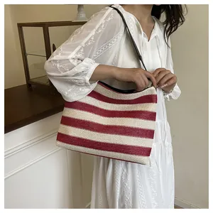 Détail du sac de plage en paille rayé rouge et blanc porté par un mannequin en dentelle
