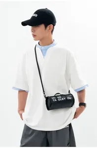 Detail of a black cylindrical crossbody bag with white letter print on a casual outfit