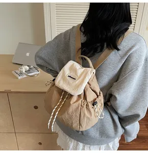 Détail de la fermeture à cordon et du rabat contrasté sur un sac à dos en nylon kaki