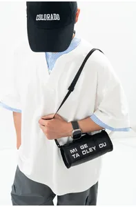 Detail of black cylindrical nylon crossbody bag with white typography and adjustable strap