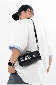 Macro view of black cylindrical crossbody bag featuring bold white letter printing detail