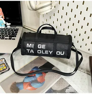 Detail of black cylindrical nylon bag with bold white lettering on a glass desk