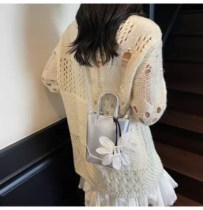 Detail of silver metallic mini bucket bag with white fabric flower charm and long strap