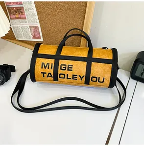 Detail of yellow cylindrical crossbody bag featuring textured fabric and bold black lettering