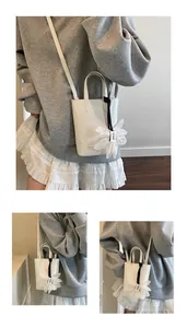 Detail of white mini bucket bag with mesh flower pendant and detachable strap