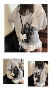 Glossy black mini bucket bag with white flower charm and slim strap detail shot
