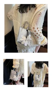 Detail of silver metallic mini tote bag with a white floral charm and thin shoulder strap
