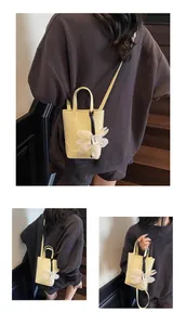 Detail of yellow bucket bag with floral charm and FASHION & BAGS leather logo text