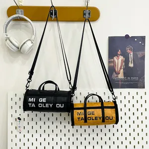 Stylish cylinder-shaped shoulder bag in black and mustard yellow with bold printed text