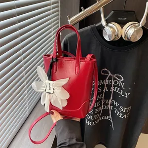 Chic red mini bucket bag with white flower charm and adjustable shoulder strap