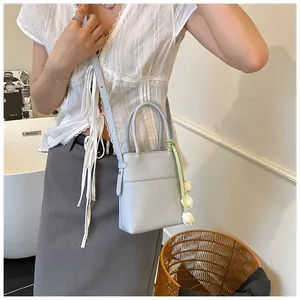 Close-up of light blue leather mini handbag with elegant white tulip floral charm