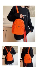 Detailaufnahme des orangefarbenen Mini-Rucksacks mit Nylontextur und Kordelzug-Reißverschlüssen