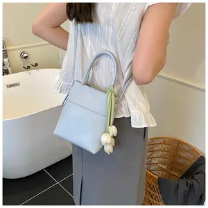 Detail of light blue bucket bag with silk scarf and tulip charm in indoor scene