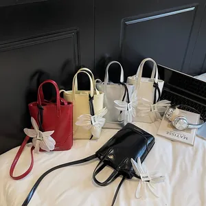 Minimalist bucket bags in five colors with oversized floral charms on white bedding
