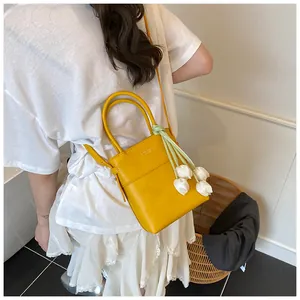 Detail of yellow mini bucket bag with elegant tulip pendant and adjustable shoulder strap
