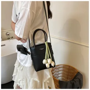 Detail of black mini bucket bag with tulip charm and white fashion text branding