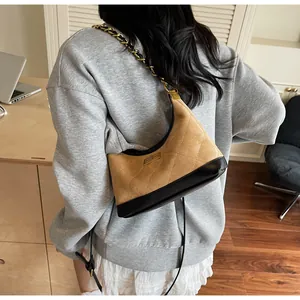Sac bandoulière matelassé en daim marron avec chaîne dorée porté par un mannequin
