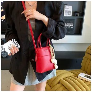 Detailed view of a mini red crossbody bag with tulip charm worn on a black blazer