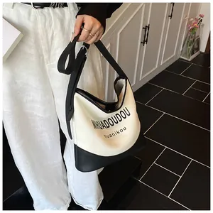 Détail du sac cabas en toile avec garniture en cuir noir et bandoulière portées