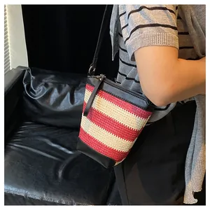 Primo piano della borsa a secchiello tessuta a righe rosse e bianche con tracolla in pelle nera