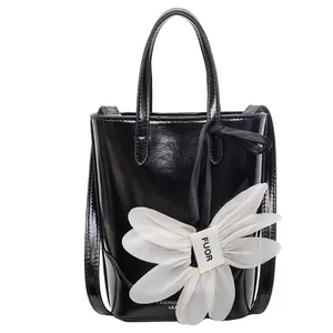 Glossy black patent leather bucket bag with white organza flower charm for women