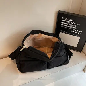 Große schwarze Umhängetasche aus Nylon mit mehreren Taschen auf Marmorboden