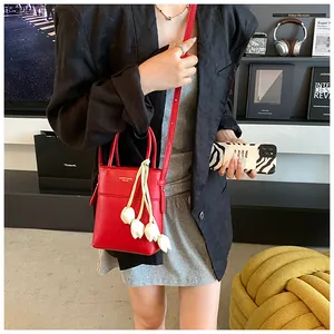 Detailed view of a red mini tote bag with white tulip charm worn as a crossbody bag