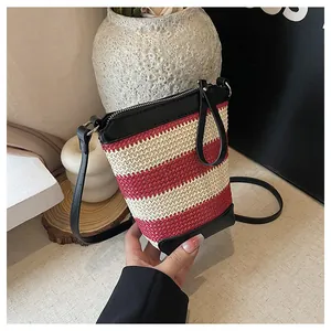 Dettaglio della borsa a secchiello a righe rosse e crema con finiture in pelle nera e zip