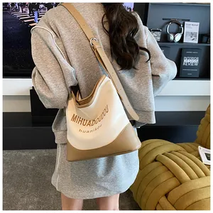 Détail du sac seau en toile avec garniture en cuir et bandoulière réglable sur le mannequin