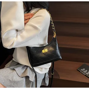 Détail d'un sac en cuir noir matelassé avec chaîne dorée sur un escalier en bois