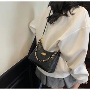 Détail du sac bandoulière en cuir noir matelassé avec chaîne dorée et fermoir pivotant