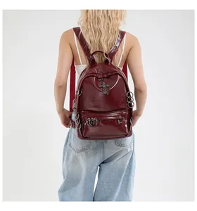 Vue détaillée du sac à dos punk bordeaux avec croix argentée porté par le mannequin