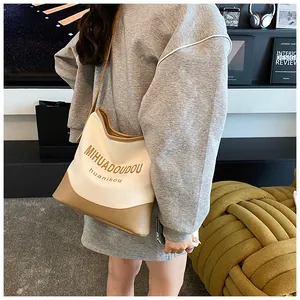 Détail du sac fourre-tout en toile avec finitions en cuir et bandoulière sur mannequin