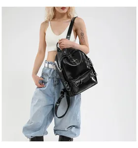 Détail du sac à dos noir brillant avec anneaux métalliques punk et zips en croix