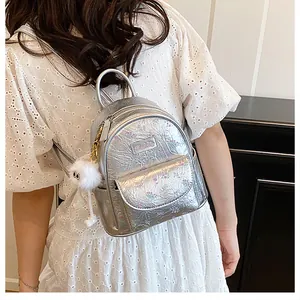 Detail of silver mini backpack with floral print, metallic texture and plush ball charm