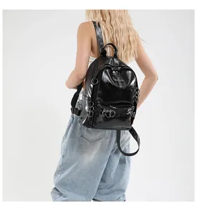 Détail d'un sac à dos gothique noir brillant avec anneaux en métal et pendentif croix