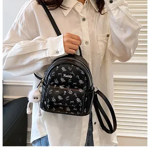 Detail of floral mini backpack with furry monster charm and Heddy brand label