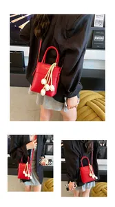 Detail of red leather mini bag featuring unique tulip pendant and sleek top handle
