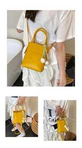 Detail of yellow mini bucket bag featuring a white tulip charm and leather strap