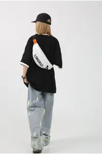 Rear view of model wearing white Oxford chest bag with black strap and orange label detail