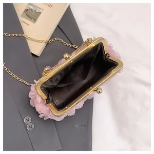 Macro detail of pink floral evening bag with gold clasp and dark fabric lining