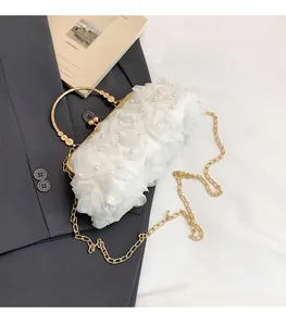 Detail of white evening bag with chiffon roses, pearls, and gold ring handle