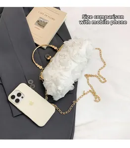 Detailed size comparison of the white floral evening bag next to an iPhone