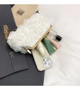 Interior view of white pearl floral evening bag holding a smartphone and perfume