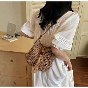 Close-up of woven straw crossbody bag with leather strap and decorative tassels