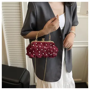 Detail of burgundy evening clutch with 3D chiffon roses and pearl accents on chain