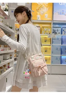 Pink canvas shoulder bag featuring a cute bow and colorful plush ball charm decoration